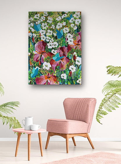 A colorful  original floral canvas wall art hanging on a white wall above a pink armchair and a small side table with cups, framed by green plant leaves.